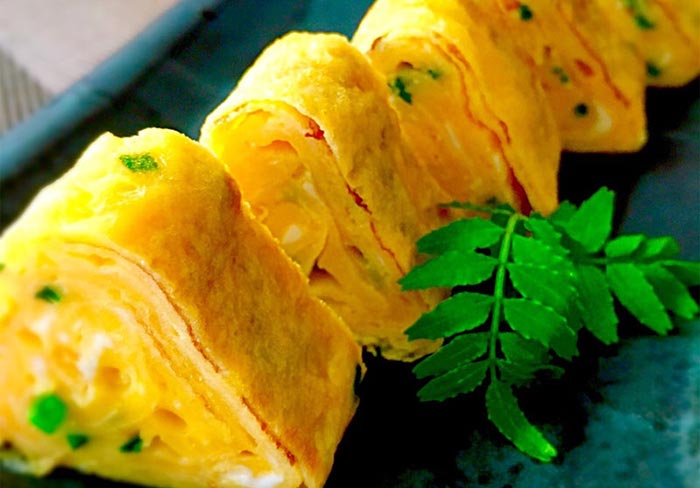 La manipolazione finale della forma della frittata Tamagoyaki con la stuoietta di bambù.