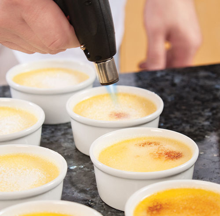La fase di caramellizzazione dello zucchero superficiale prima di servire la Crème brûlée