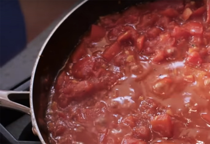 Preparazione della shakshuka con l'aggiunta del pomodoro